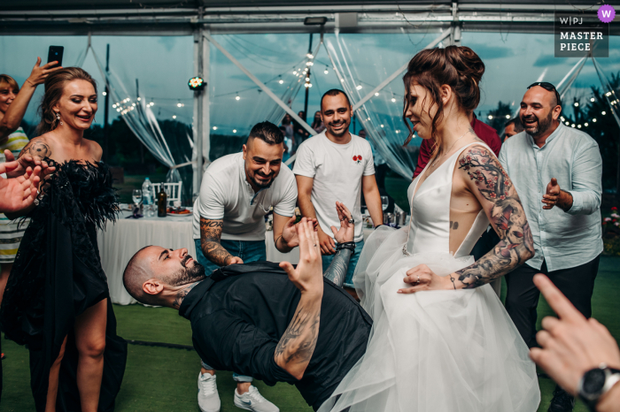 Sofia, Bulgaria outdoor marriage reception party award-winning photo that has recorded the groom gesturing - Come on, baby. The world's top wedding photographers compete at the WPJA