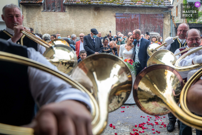 Nagrodzone zdjęcie z ceremonii zaślubin na świeżym powietrzu w Oksytanii, przedstawiające tradycyjnych muzyków grających muzykę dla młodej pary z emocjami. Najlepsze na świecie konkursy fotografii ślubnej organizowane przez WPJA