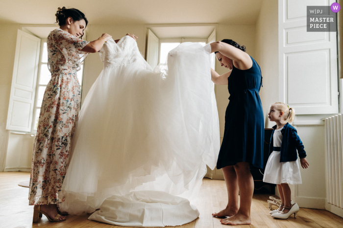 Chateau Laplaud - Oradour sur Glane marriage preparation time award-winning picture capturing the Witnesses preparing the dress as the bride's daughter slips into her mom's shoes