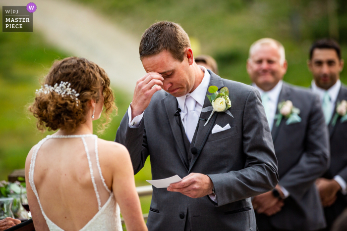 Black Mountain Lodge en Arapahoe Basin, imagen premiada de la ceremonia de matrimonio al aire libre de Keystone que muestra al novio emocionado mientras lee sus votos matrimoniales a su novia. Los mejores concursos de fotografía de bodas del mundo presentados por la WPJA