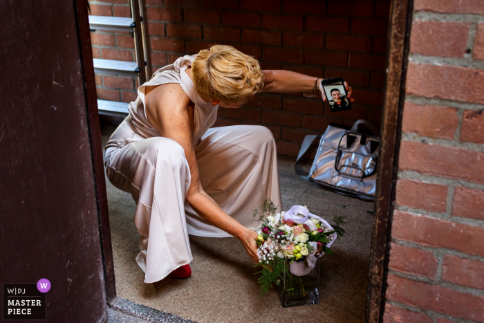 Amsterdam nuptial day award-winning image of the mom showing her self-made flower bouquet to friend in a videocall. The world's best wedding photography competitions are hosted by the WPJA