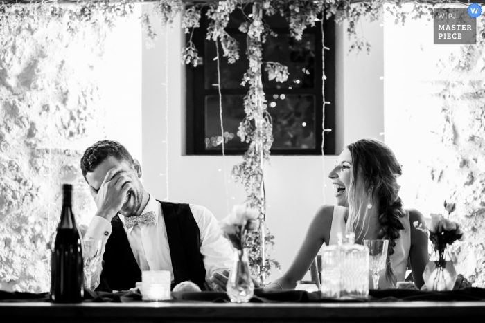 Foto premiada de festa de recepção de casamento em ambiente fechado no Château Saint Denis, França, mostrando risadas de BW na mesa principal