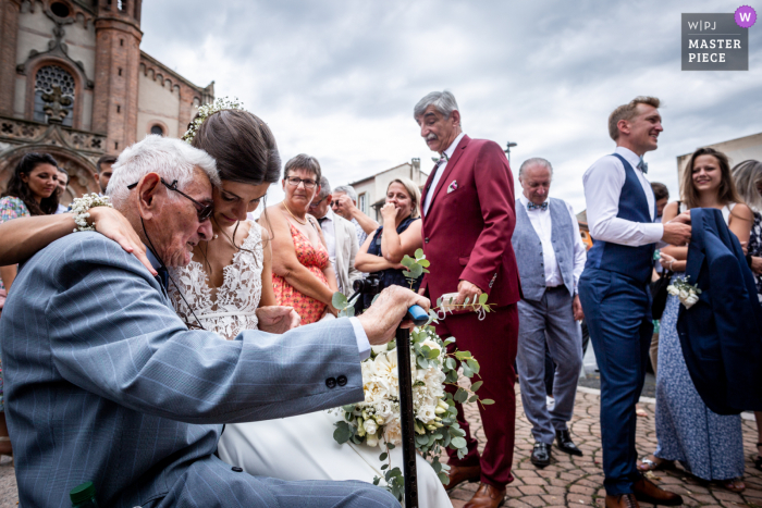 Immagine premiata per la cerimonia di matrimonio all'aperto del municipio di Carmaux che mostra un momento emozionante tra la sposa e suo nonno dopo la cerimonia. I migliori concorsi fotografici di matrimonio al mondo presentati dal WPJA