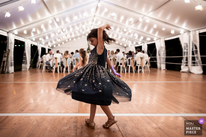 Château du Vergnet, Tarn, réception de mariage en plein air photo primée qui a enregistré une petite fille dansant pendant que tout le monde mange. Les meilleurs photographes de mariage au monde concourent à la WPJA