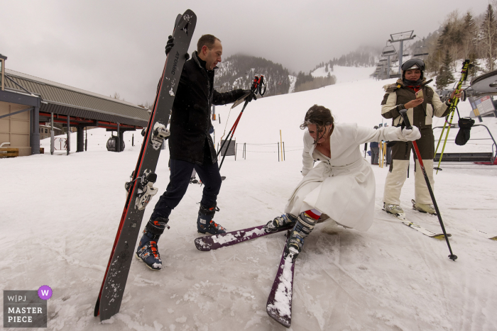 Imagem vencedora do prêmio do dia nupcial do Aspen Mountain Resort da noiva caindo após esquiar na montanha após sua cerimônia de micro casamento