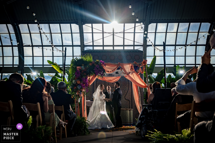 Photo by: <a href="https://www.wpja.com/contests/2021-v02/best-wedding-photographers/2631831">Victoria Sprung - Chicago Illinois</a> Garfield Park Conservatory, Chicago indoor wedding reception party award-winning picture showing a ceremony in a greenhouse