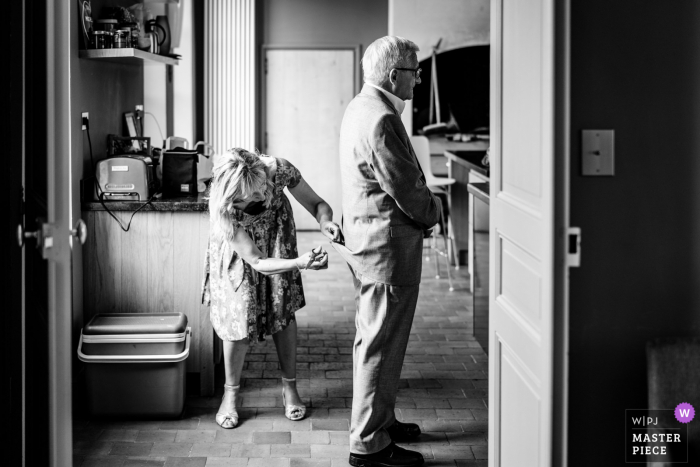 Domaine de Toury, France temps de préparation du mariage capture d'une photo primée La mère de la mariée coupe un fil à coudre sur la veste du grand-père