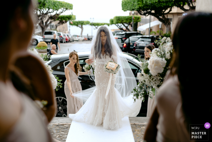 Italy nuptial day award-winning image of the bride adjusting her veil outdoors before entering the church Italy nuptial day award-winning image of the bride adjusting her veil outdoors before entering the church