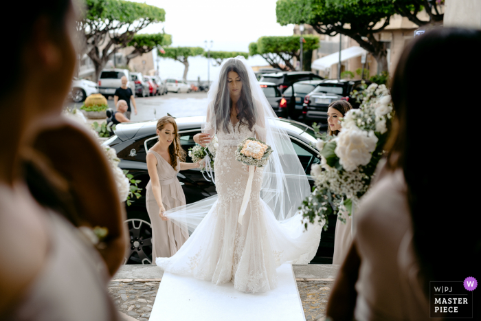 Immagine premiata per il giorno delle nozze in Italia della sposa che si aggiusta il velo all'aperto prima di entrare in chiesa