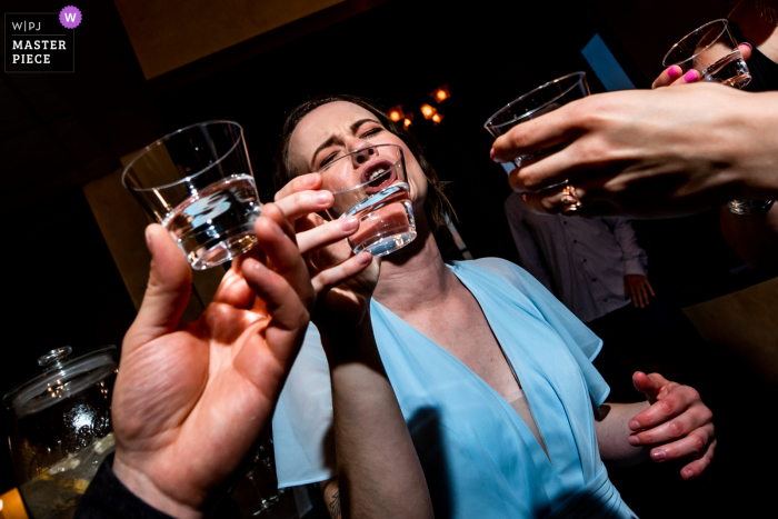 Historic Concord Exchange, Minnesota indoor wedding reception party award-winning picture showing a Bridesmaid does a shot