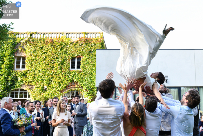 Lille outdoor marriage reception party award-winning photo that has recorded the bride’s relatives trying to throw her in the air