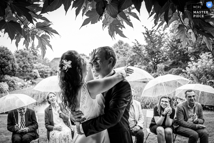 Landgoed Tielen, imagen ganadora del premio de matrimonio al aire libre de Hoeven que muestra que durante la ceremonia bajo la lluvia, la novia limpia la lluvia del novio