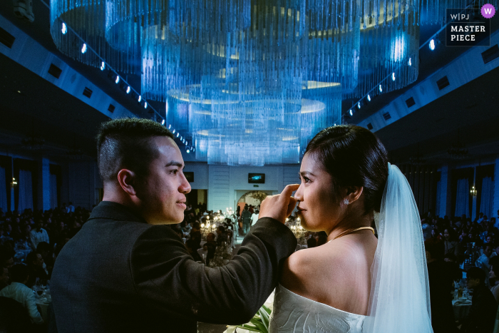 Haiphong, Vietnam bekroonde binnenhuwelijksafbeelding die bruid en bruidegom toont tijdens de ceremonie. 'S Werelds beste trouwfotowedstrijden worden aangeboden via de WPJA