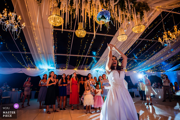 Foto premiada de festa de recepção de casamento em recinto fechado de Marina Cape, Aheloy, Bulgária mostrando o lançamento do Bouquet. Os fotógrafos de casamento mais qualificados do mundo são membros da WPJA