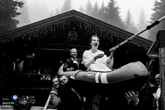 Chalet du Loup outdoor marriage reception party award-winning photo that has recorded the Couple getting carried on a canoe during cocktail hour. The world's top wedding photographers compete at the WPJA