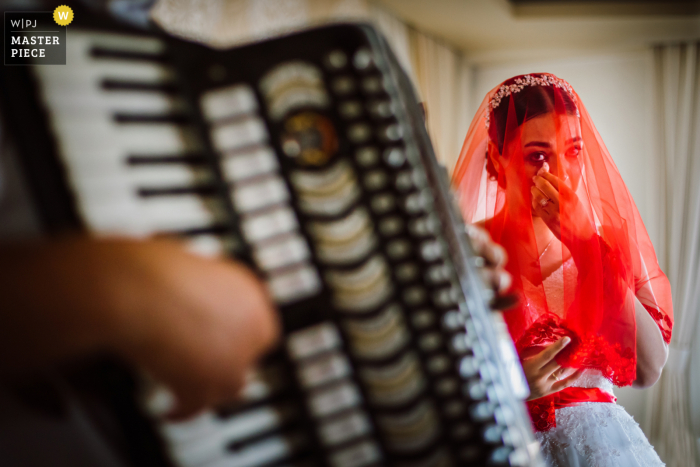 Bodrum, Turkey nuptial day award-winning image of Bride saying goodbye to her family with traditional accordion goodbye song. The world's best wedding photography competitions are hosted by the WPJA