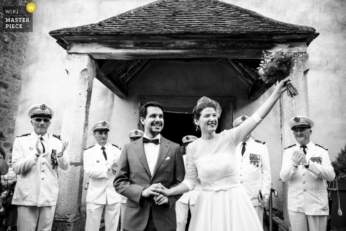 Image primée de la cérémonie de mariage à Lyon montrant la sortie de l'église des mariés avec une garde d'honneur militaire. Les meilleurs concours de photos de mariage au monde sont présentés via le WPJA