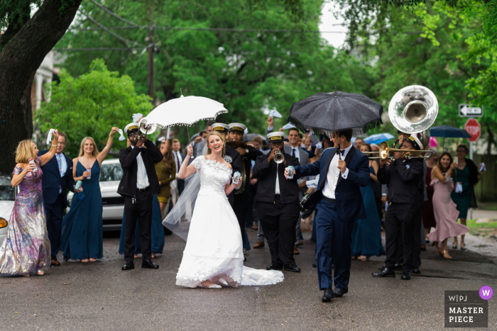 New Orleans, LA, preisgekröntes Bild eines Brautpaares, das während ihrer regnerischen April-Hochzeit in New Orleans die zweite Reihe durch die Straßen von Uptown führt.