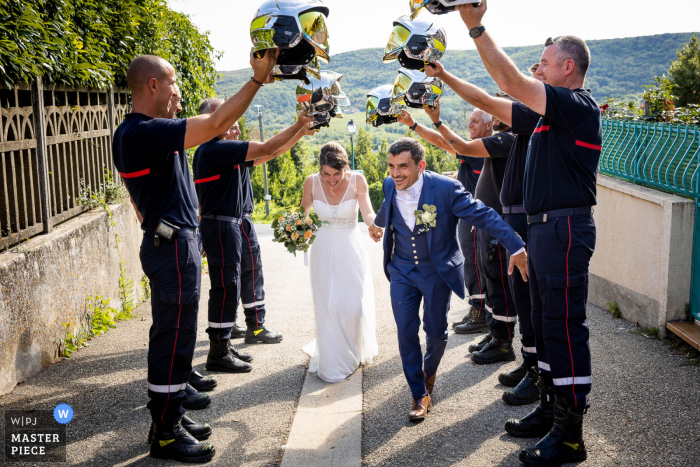 Foto premiada da festa de recepção de casamento ao ar livre na França que registra amigos bombeiros formando túneis com capacetes. Os melhores fotógrafos de casamento do mundo competem no WPJA