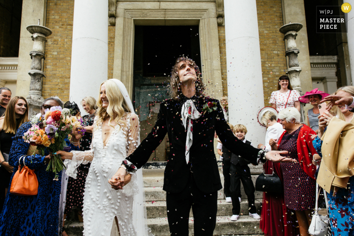 Imagem premiada de festa de recepção de casamento em Manchester, Reino Unido, mostrando o noivo tomando banho de confete. Os fotógrafos de casamento mais qualificados do mundo são membros da WPJA