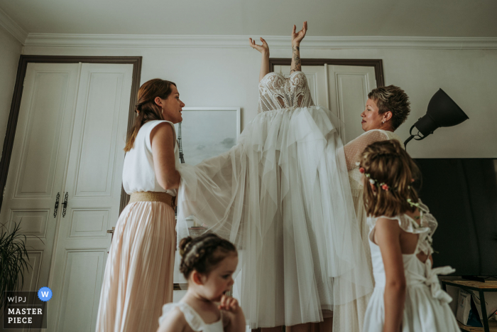 Saint Porchaire, Charente-Maritime marriage preparation time award-winning picture capturing The bride putting on her dress. The world's best wedding image competitions are held by the WPJA