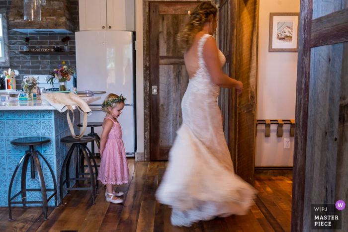 Colorado Ehevorbereitungszeit preisgekröntes Bild, das die Braut einfängt, die dem Blumenmädchen das Kleid zeigt. Die weltbesten Hochzeitsbildwettbewerbe werden von der WPJA veranstaltet