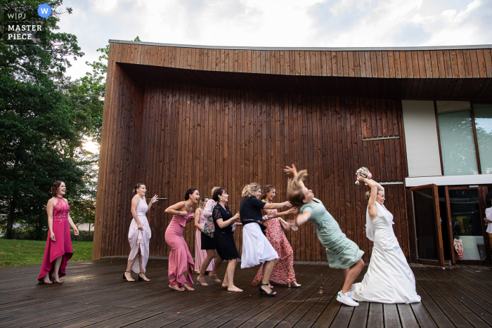 Grand Est Outdoor-Hochzeitsempfangsparty preisgekröntes Foto, das aufgezeichnet hat Ein Mädchen, das auf den Strauß fällt. Die besten Hochzeitsfotografen der Welt messen sich bei der WPJA