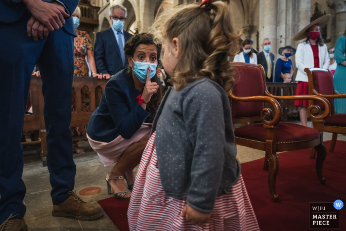 Église Saint Cast, France, cérémonie de mariage en salle, image primée montrant la sœur et la fille de la mariée. Les meilleurs concours de photos de mariage au monde sont présentés via le WPJA