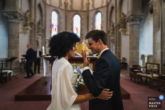 Image primée de la cérémonie de mariage à l'intérieur de Saint Cast, France montrant le couple dans l'église Tout juste marié. Les meilleurs concours de photos de mariage au monde sont présentés via le WPJA