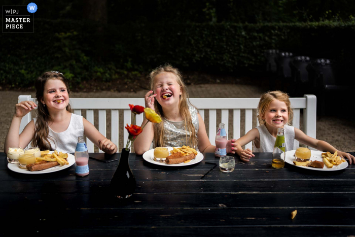 Residence Rhenen, Niederlande preisgekröntes Bild der Innenhochzeitsfeier, das zeigt, wie die Mädchen beim Essen ihrer Kinder viel Spaß haben.