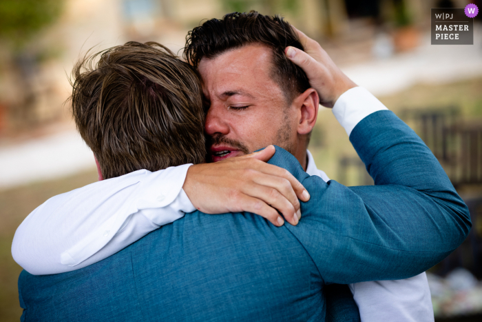 Urbino, Italy nuptial day award-winning image of the groom and friend hugging outside - from the world's best wedding photography competitions hosted by the WPJA