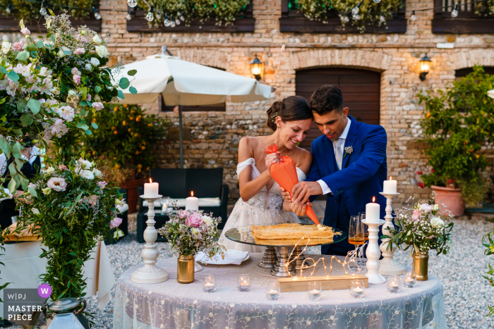 Paradiso, Pocenia, Udine marriage reception party award-winning photo that has recorded the Bride and groom setting the cake Paradiso, Pocenia, Udine marriage reception party award-winning photo that has recorded the Bride and groom setting the cake - from the world's best wedding photography competitions offered by the WPJA