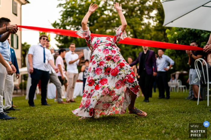 Villa Rigatti, Fiumicello, Udine marriage reception party award-winning photo that has recorded the outdoor Limbo game on the grass - from the world's best wedding photography competitions offered by the WPJA