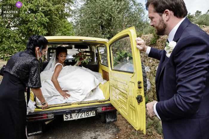 Pieve di San Pietro, Gropina preisgekröntes Bild der Braut, die nach der Zeremonie die Kirche im Fond des Autos verlässt - von den weltweit besten Hochzeitsfotografie-Wettbewerben der WPJA