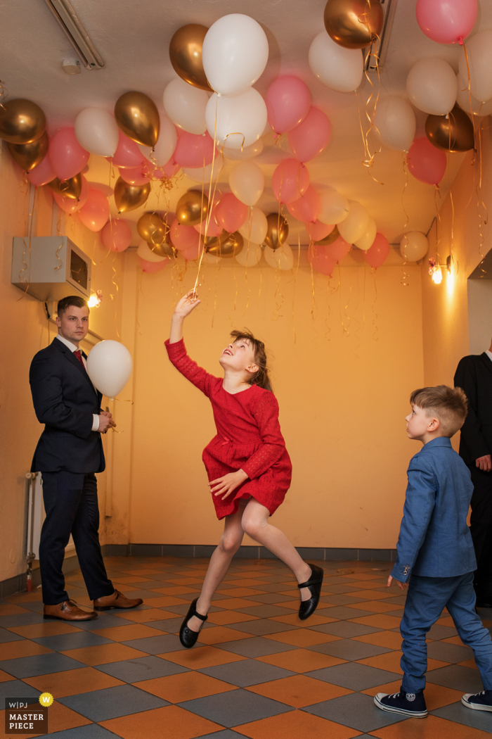 Krakow marriage reception party award-winning photo that has recorded a girl jumping for a balloon - from the world's best wedding photography competitions offered by the WPJA