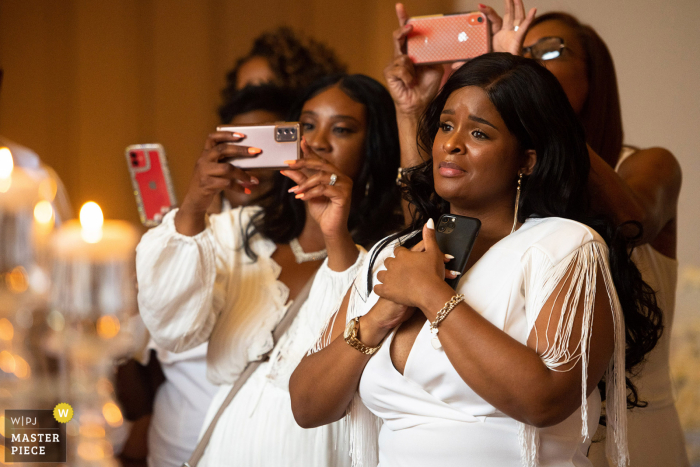 Georgetown Center, festa de recepção de casamento em Pittsburgh - foto premiada que gravou Uma amiga de faculdade da noiva segurando seu coração enquanto observa o novo casal - nos melhores concursos de fotografia de casamento do mundo oferecidos pela WPJA