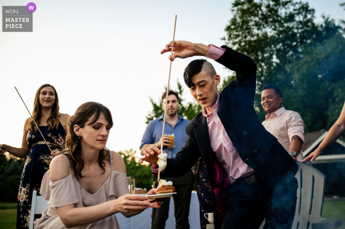1824 House - Waitsfield, Vermont marriage reception party award-winning photo that has recorded Guests making s'mores over a fire during the reception 1824 House - Waitsfield, Vermont marriage reception party award-winning photo that has recorded Guests making s'mores over a fire during the reception - from the world's best wedding photography competitions offered by the WPJA