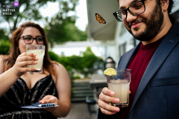 Essex Resort - Essex, Vermont, preisgekröntes Foto der Hochzeitsfeier, das aufgenommen wurde Ein Schmetterling, der die Cocktailstunde besuchte, die an einem Getränk der Gäste interessiert war - aus den weltweit besten Hochzeitsfotografie-Wettbewerben, die von der WPJA angeboten werden