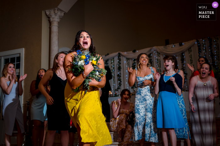 Photo by: <a href="https://www.wpja.com/contests/2021-v02/best-wedding-photographers/2635006">Johnny Shryock - Arlington Virginia</a> Morais Vineyard, Bealeton marriage reception party award-winning photo that has recorded bridesmaid catching a bouquet - from the world's best wedding photography competitions offered by the WPJA