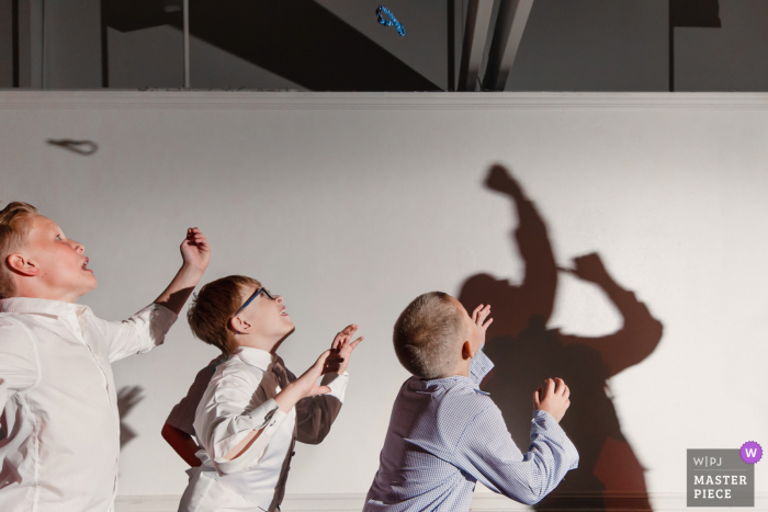 Arrowhead Golf Course, Littleton, CO marriage reception party award-winning photo that has recorded the Kids are poised to jump for the garter, with the grooms shadow on the wall - from the world's best wedding photography competitions offered by the WPJA