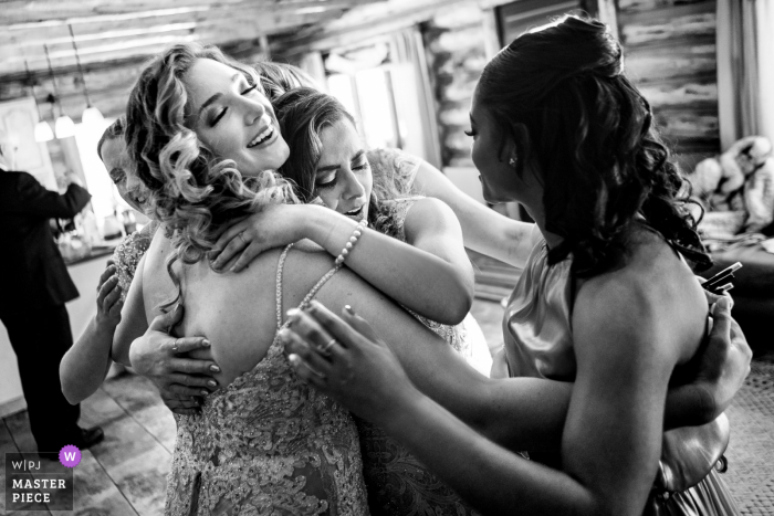 Imagen premiada del día nupcial de Pagosa Springs, CO de la novia abrazando a sus damas de honor el día de su boda - de los mejores concursos de fotografía de bodas del mundo organizados por la WPJA