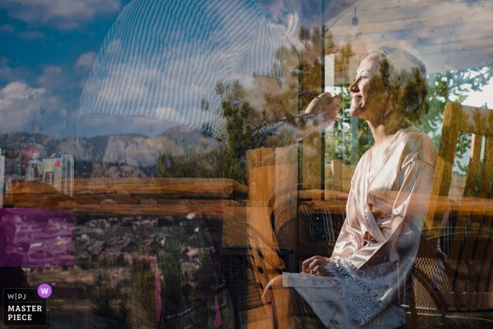 Estes Park, Colorado maakt zich klaar voor het huwelijk bekroonde foto's vastleggen De bruid laat haar make-up doen achter de weerspiegeling van de bergen - van 's werelds beste huwelijksfotografiewedstrijden gehouden door de WPJA