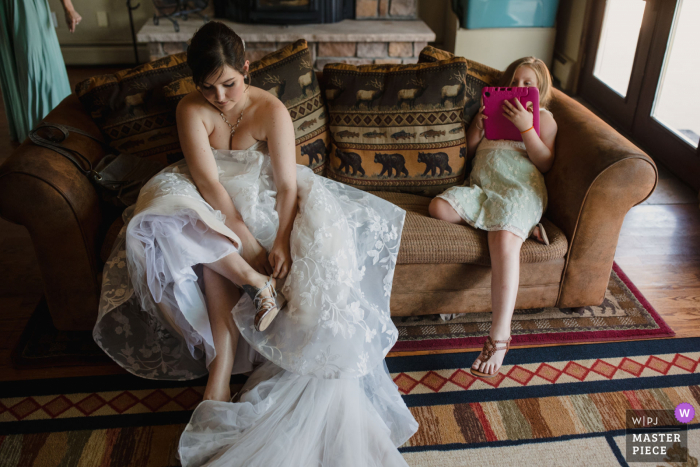 Wedgwood Weddings, Mountain View, Pine, Colorado bereitet sich auf die Ehe vor Die preisgekrönte Fotoaufnahme Braut zieht ihre Schuhe an, während ihre Nichte auf ihrem iPad spielt - von den weltweit besten Hochzeitsfotografie-Wettbewerben der WPJA