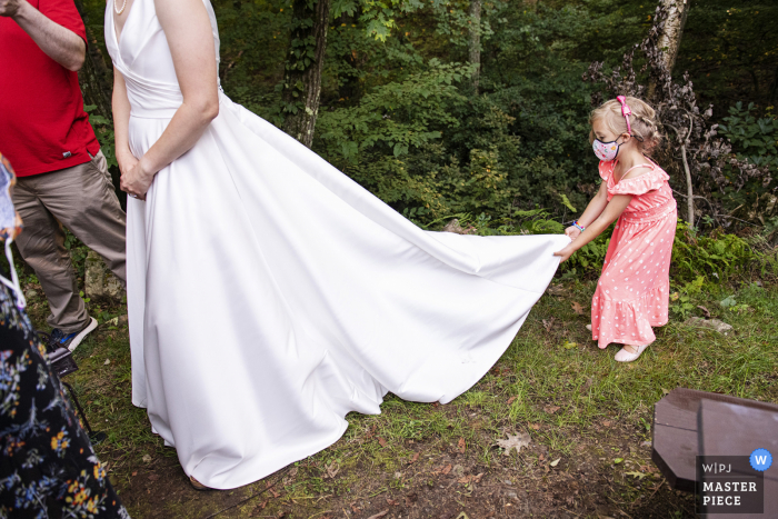 Um importante fotojornalista de casamento de Massachusetts na reserva Hale em Westwood criou esta imagem da Flower girl brincando com um vestido de noiva durante a hora do coquetel