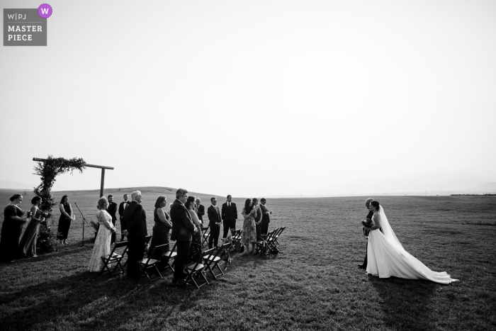 A wedding photojournalist in Emigrant, Montana captured this moment in BW of an outdoor processional under the sunshine