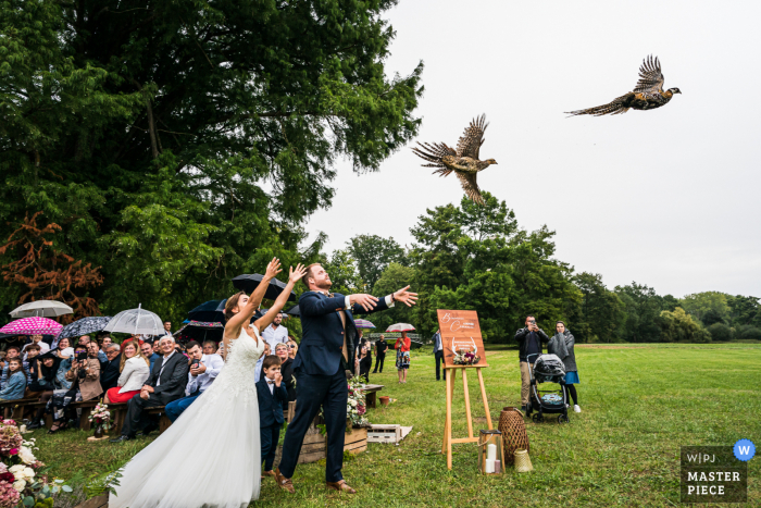 A France wedding reportage photographer captured this moment at the Château des Grotteaux of some Pheasant Throwing by the bride and groom at outdoor ceremony A France wedding reportage photographer captured this moment at the Château des Grotteaux of some Pheasant Throwing by the bride and groom at outdoor ceremony