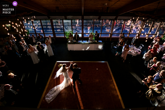 Veja esta imagem dramática de casamento tirada no Crest Center em Asheville, NC, da noiva e do noivo fazendo sua grande entrada iluminada por luz natural que entra pelas janelas