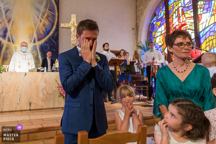 Regardez cette photo de mariage à un moment charnière à l'église alors que le marié découvre sa future épouse en tenue de mariage.