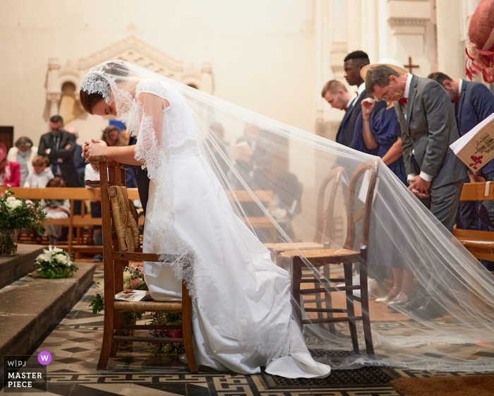 Bekijk dit belangrijke moment trouwfoto in de kerk met het licht van het glas-in-lood komt om de sluier van de bruid te verlichten tijdens de wijding