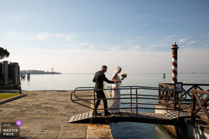 Un fotoperiodista de bodas de primer nivel en el Hotel Kempinski en la isla de San Clemente en Venecia creó esta imagen de la novia y el novio llegando al barco taxi después de Getting Ready